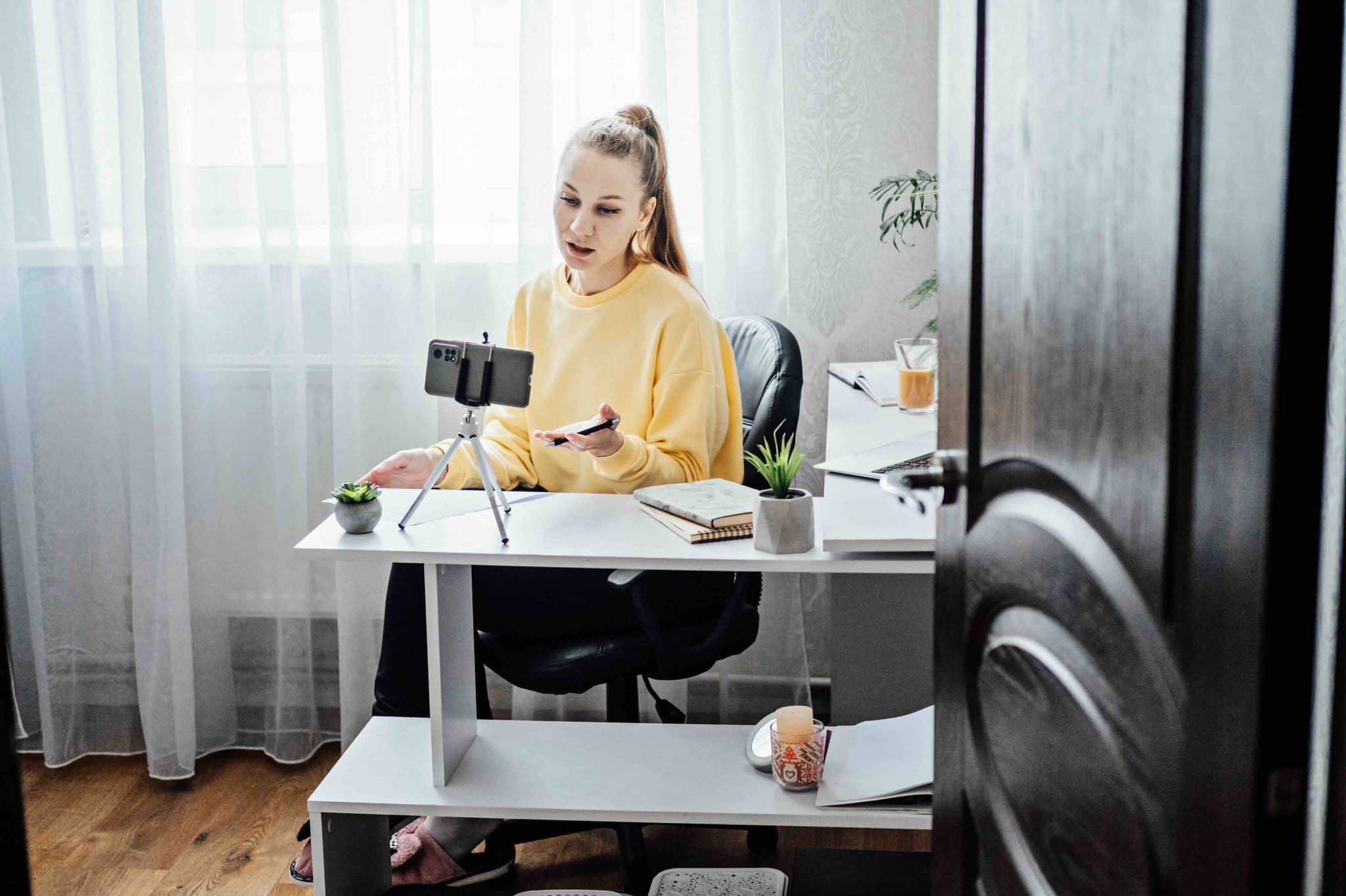 Women in yellow jumper, talking to phone on tripod