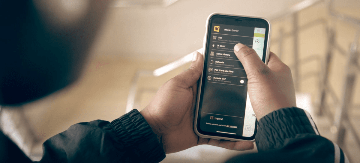 A personal holding a smartphone, using ikhokha app to sell airtime on iphone